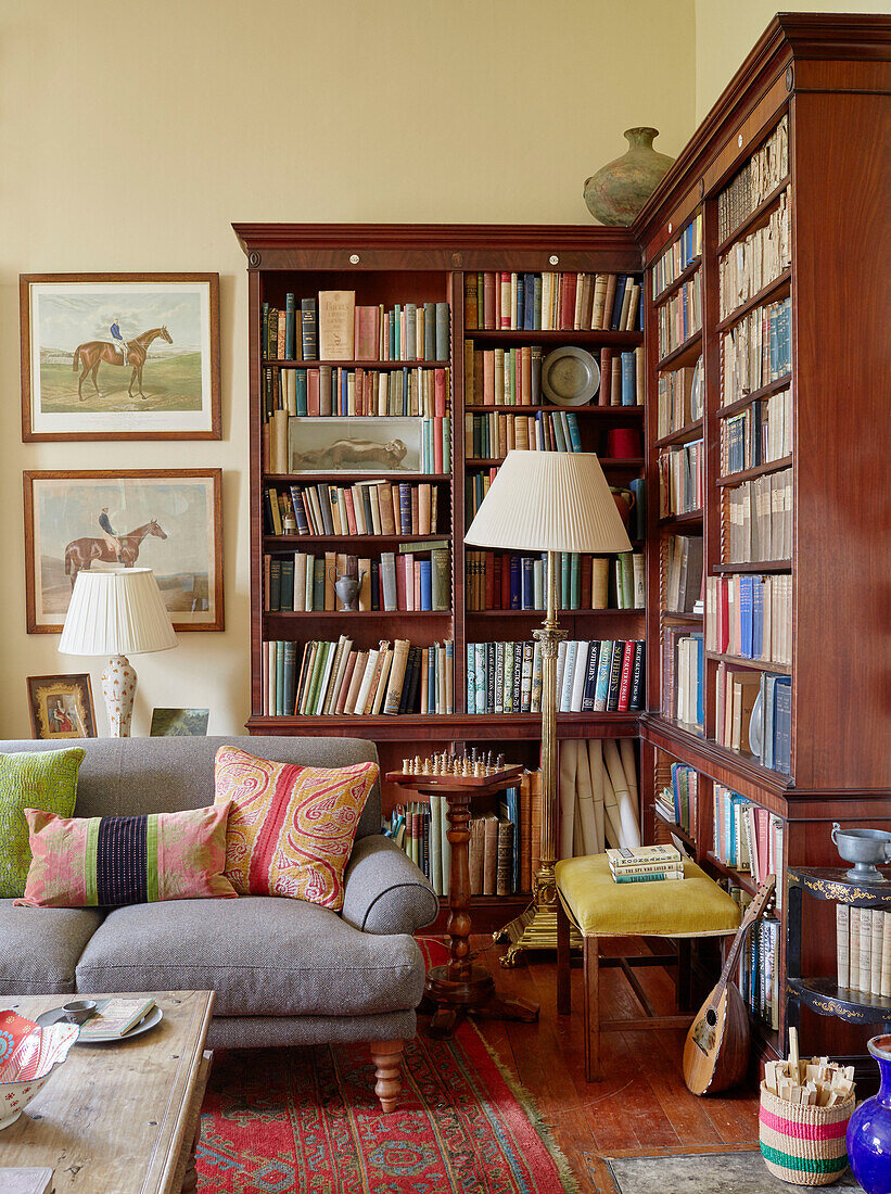 Stehlampen und Bücherregal mit grauem Sofa im Wohnzimmer Capheaton Hall in Northumberland, UK