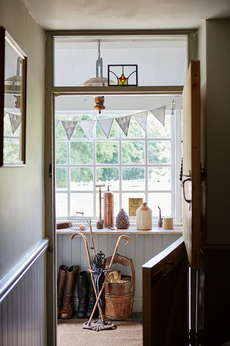 Boots and walking sticks viewed through stable door in porch of Northumberland cottage, Tyne and Wear, England, UK