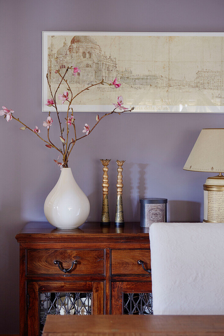 Vase of flowers with etching on lilac wall above wooden sideboard in County Durham cottage, England, UK