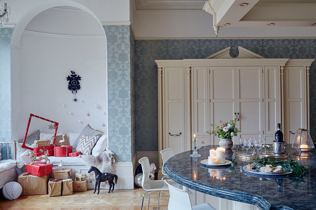 Lit candles on marble worktop with gift wrapped presents in alcove seating East Grinstead home, West Sussex, UK