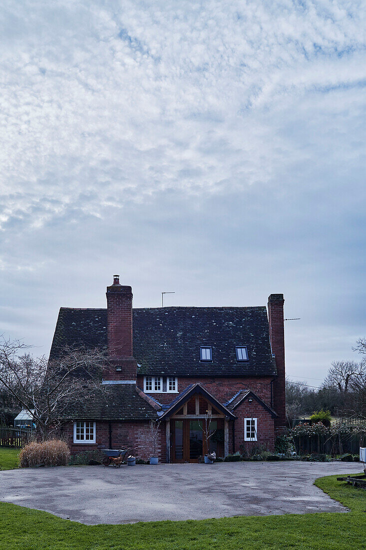 Betoneinfahrt vor einem Bauernhaus aus Backstein in Warwickshire, England, UK