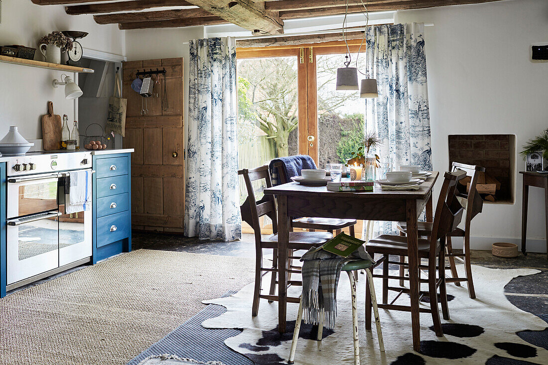 Dark wood dining table with animal skin rug in Warwickshire farmhouse kitchen England, UK