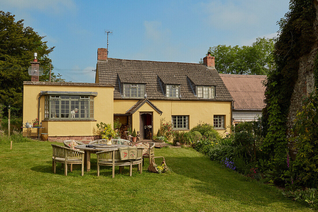 Wooden table and chairs on lawn in garden of Powys cottage, Wales