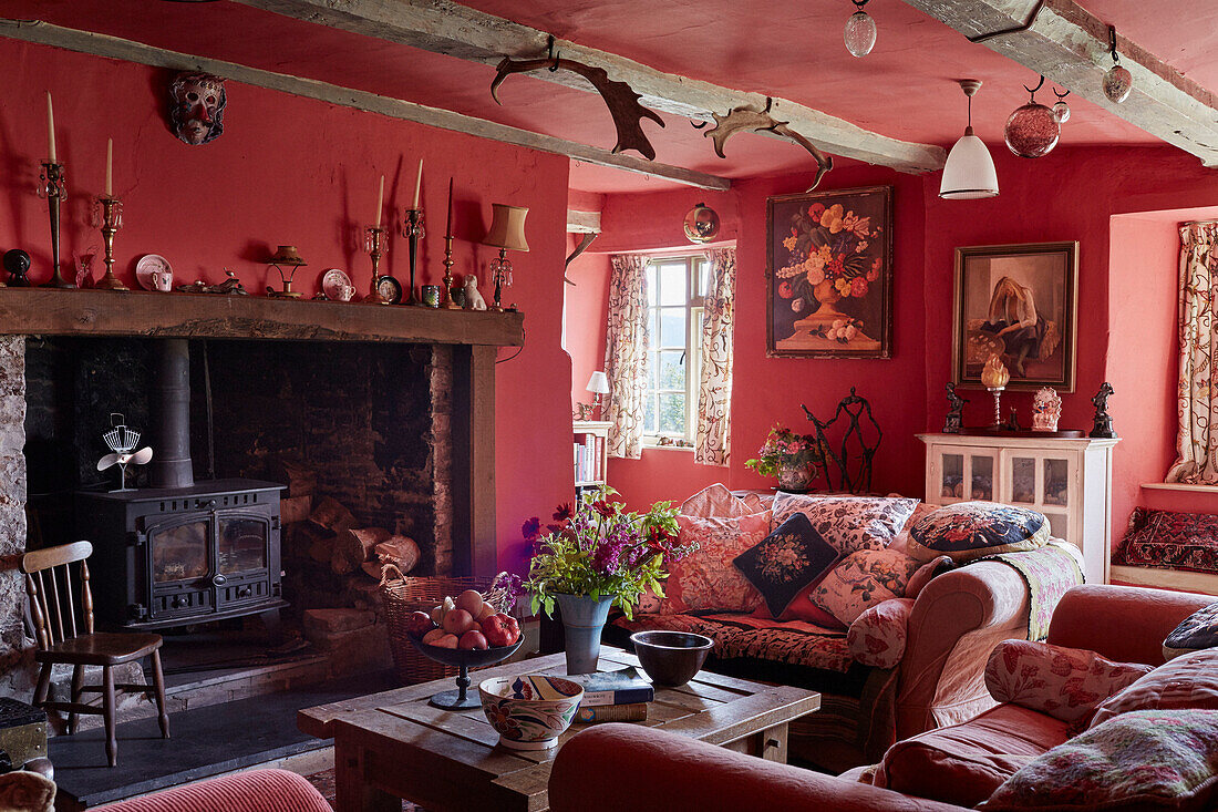 Kerzenständer auf einem Kamin mit Holzofen und Sofas in einem Wohnzimmer in Powys, Wales, UK