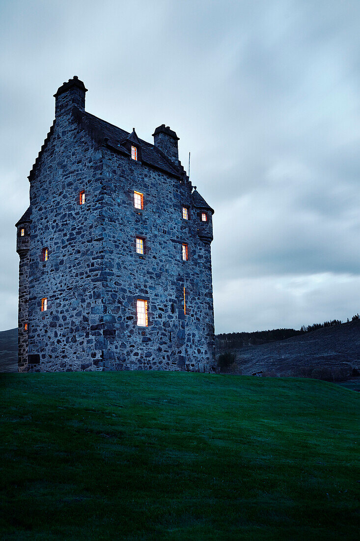 Lit windows in remote Scottish castle, UK