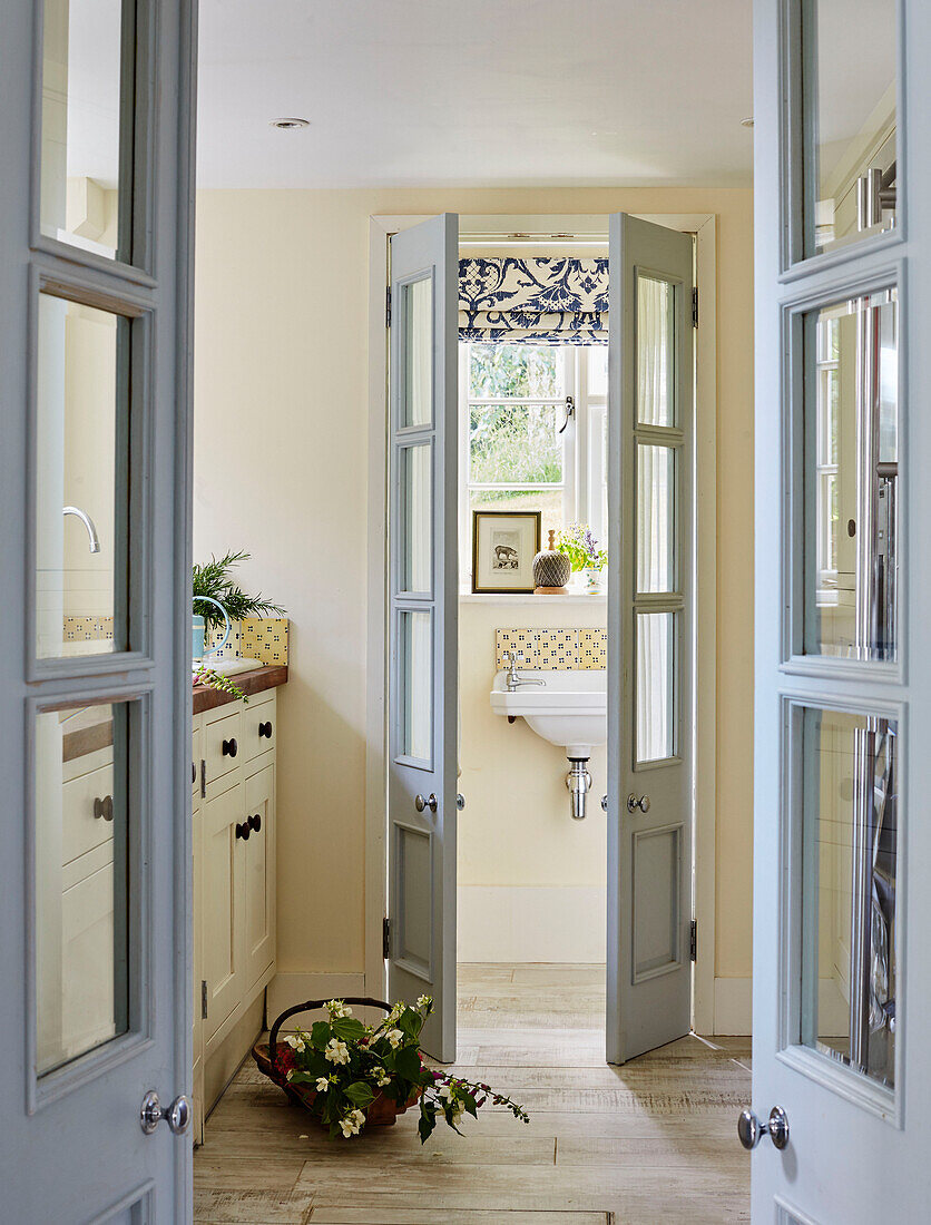 View through double doors with cut flowers in trug Sandford St Martin cottage, Oxfordshire, UK