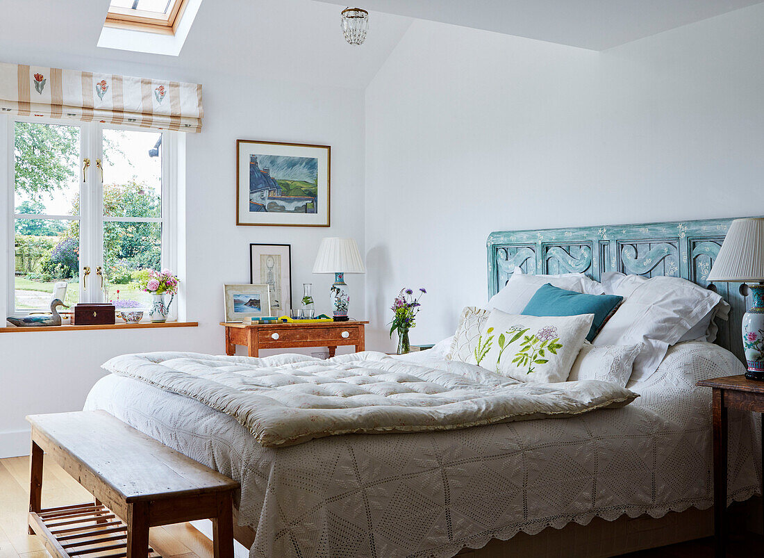White quilt on double bed with carved wooden headboard in Oxfordshire farmhouse, UK
