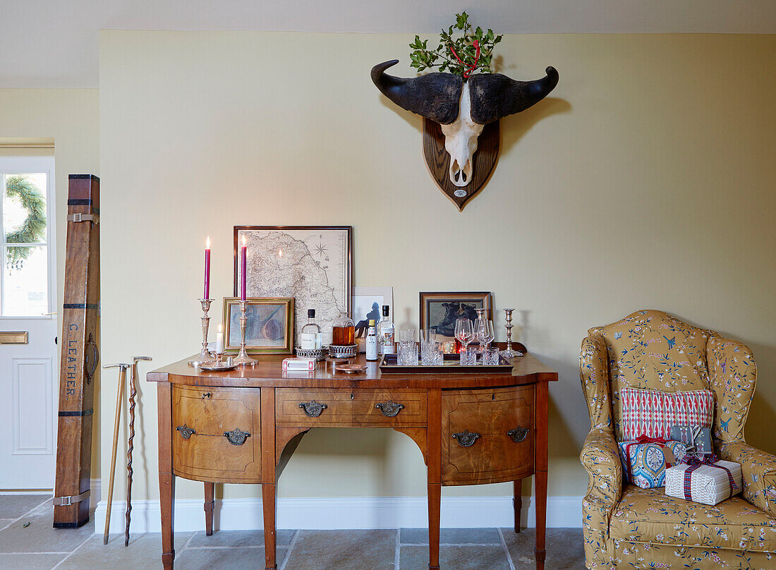 Weihnachtsgeschenke auf einem Sessel mit hölzernem Sideboard und Tierhörnern in einem Bauernhaus in Northumberland, UK