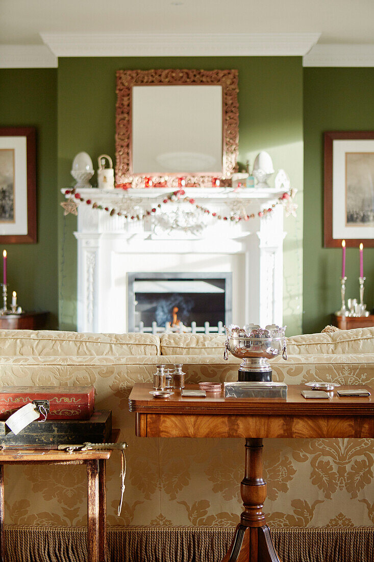 Wooden side table and sofa with mirror above fireplace in Northumberland farmhouse, UK