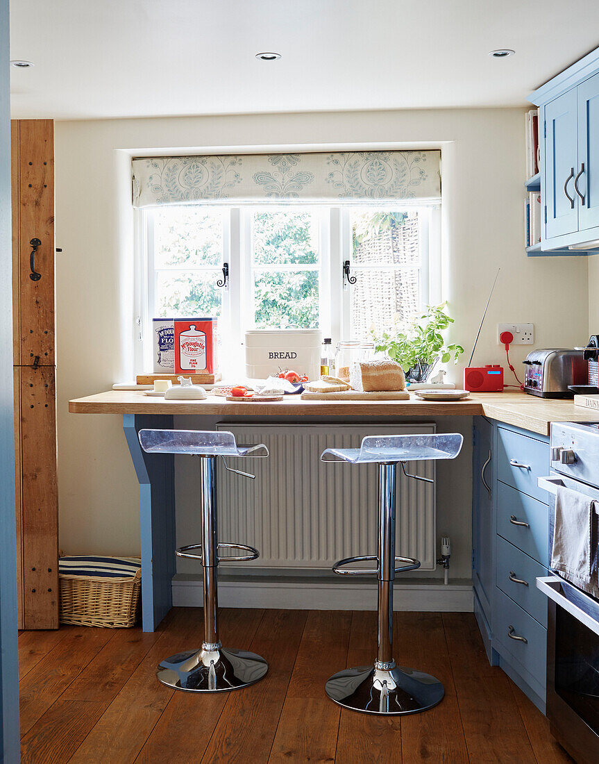 Chrome stools at breakfast bar below kitchen window in Berkshire cottage, England, UK