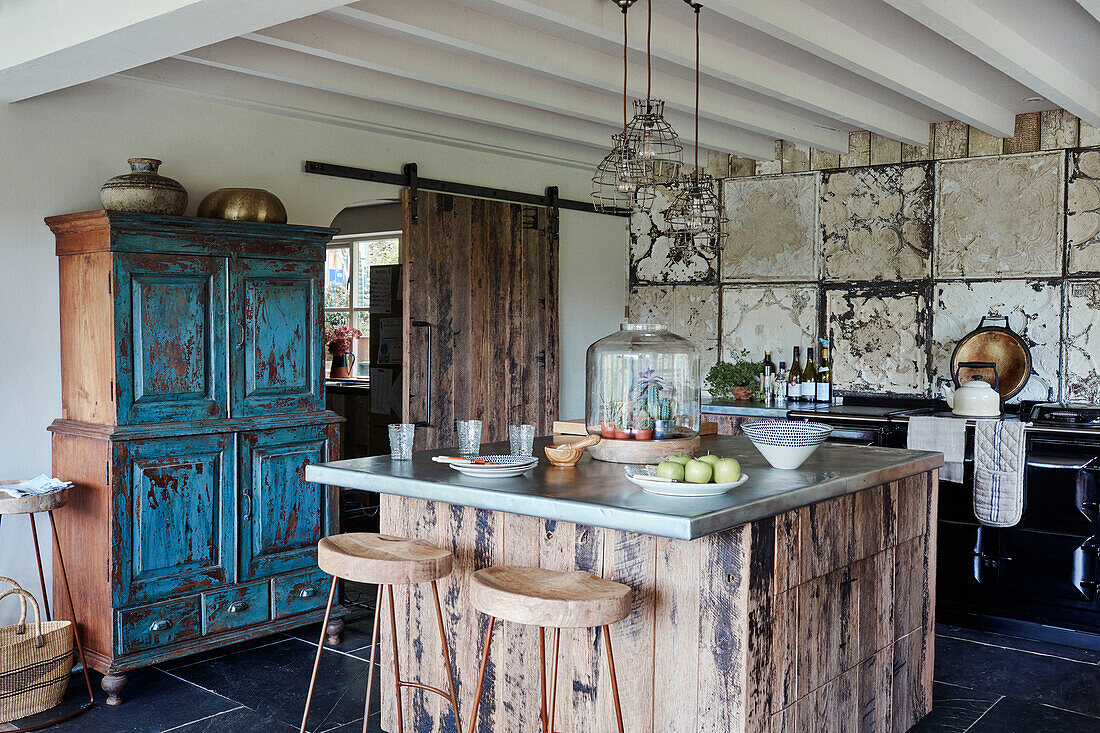 Salvaged blue dresser with barstools at island unit in Devon kitchen, UK