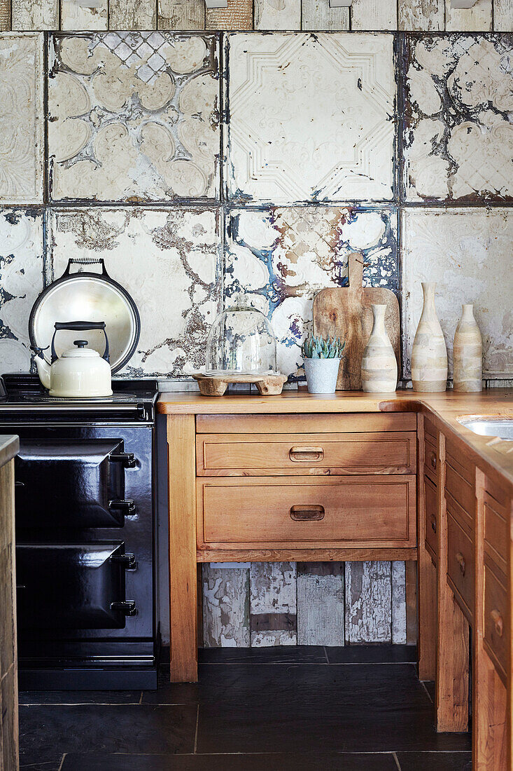 Kettle on hob with wooden drawers and distress tiling in Devon kitchen, UK