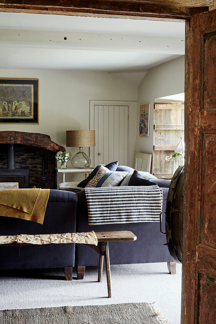 View through wooden doorway to fabrics on purple sofa in Devon living room, UK