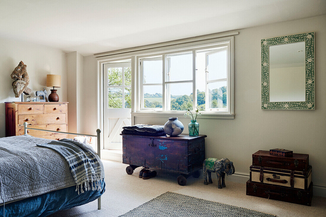 Purple locker on caster wheels below window in bedroom of Devon home, UK