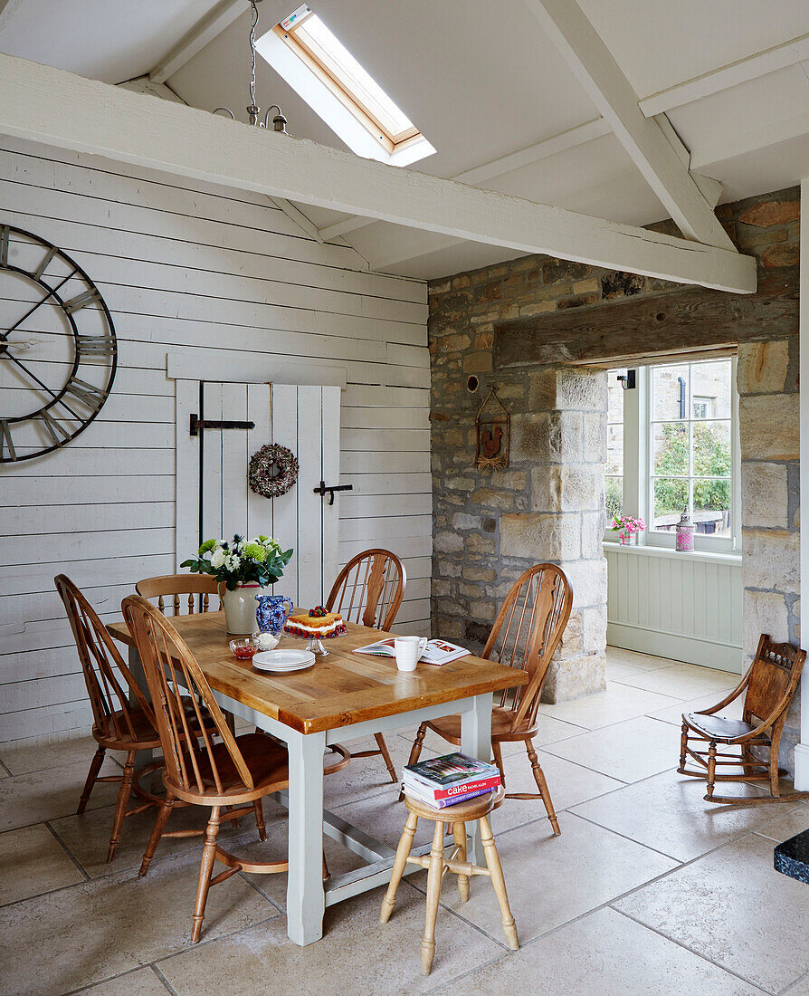 Wooden table and chairs in high beamed room of Northumberland farmhouse, UK