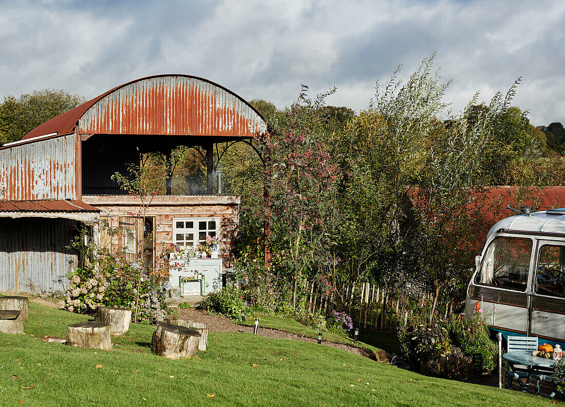 Garden with Majestic bus beside Dutch barn near Hay-on-Wye, Wales, UK