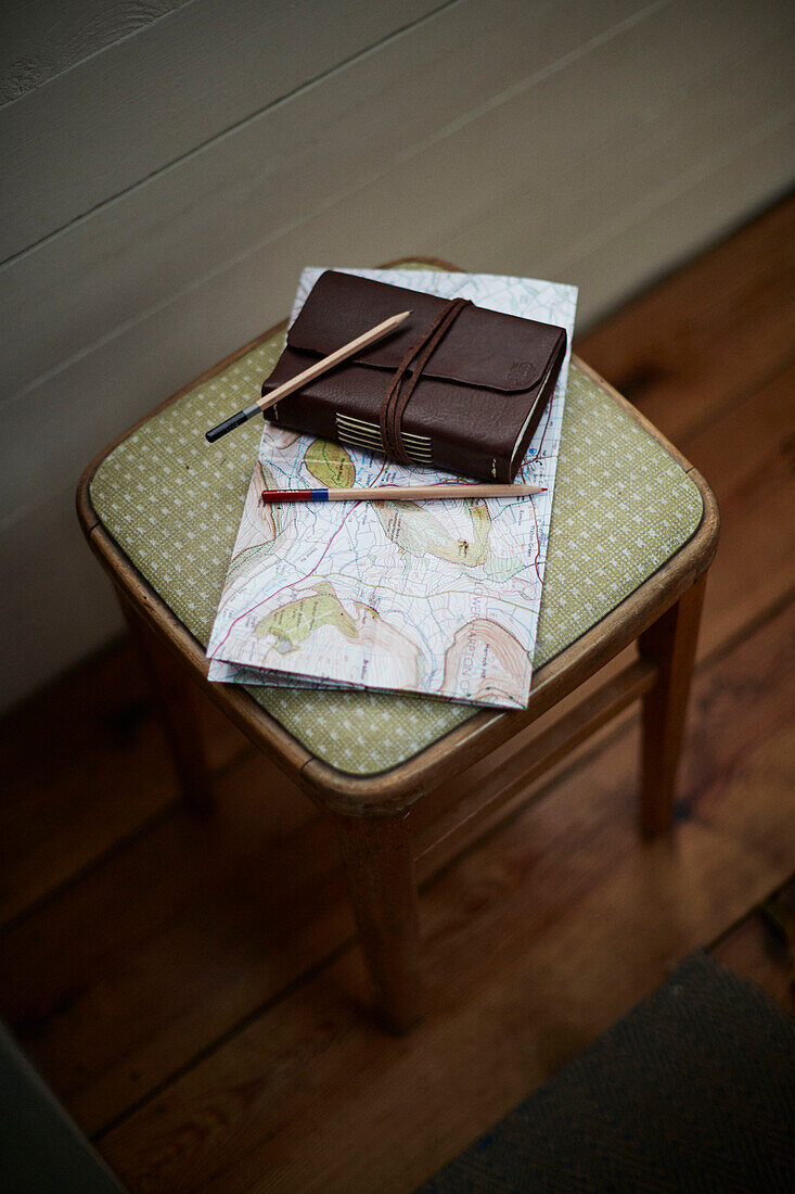 Map and sketchbook with pencils on stool inside The Majestic bus near Hay-on-Wye, Wales, UK