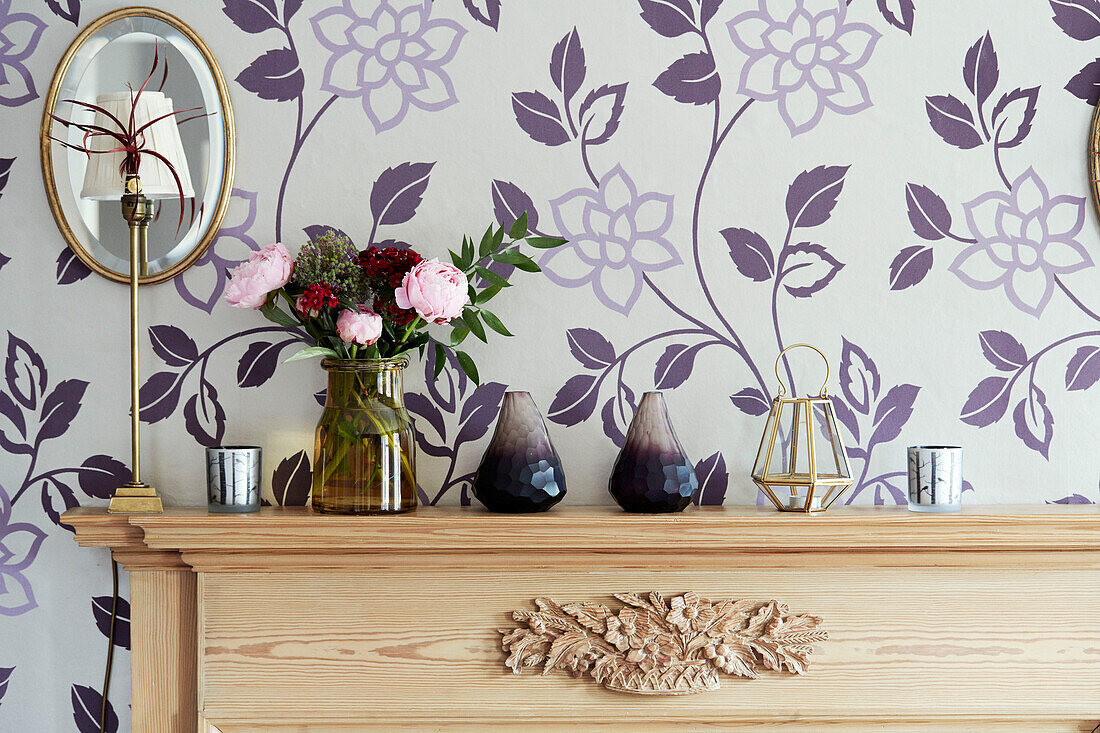 Cut flowers and gilt framed mirror on wooden mantlepiece in Cotswolds cottage, UK