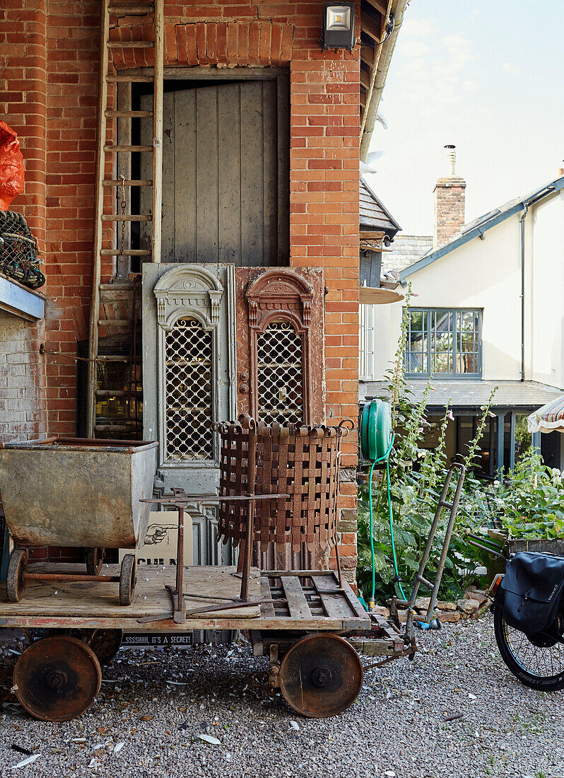 Old metal wheelbarrow and brazier with architectural salvage in Devon, UK