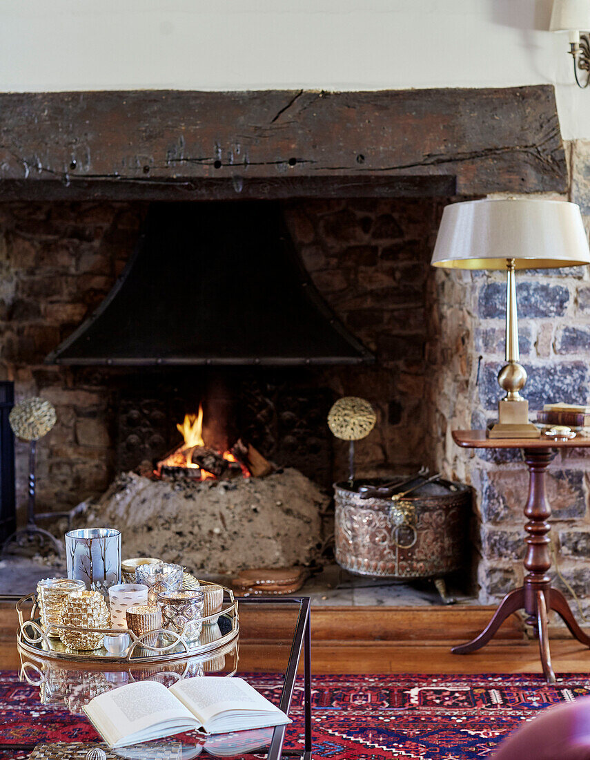 Tray of candles at exposed stone fireside in Devon home, UK