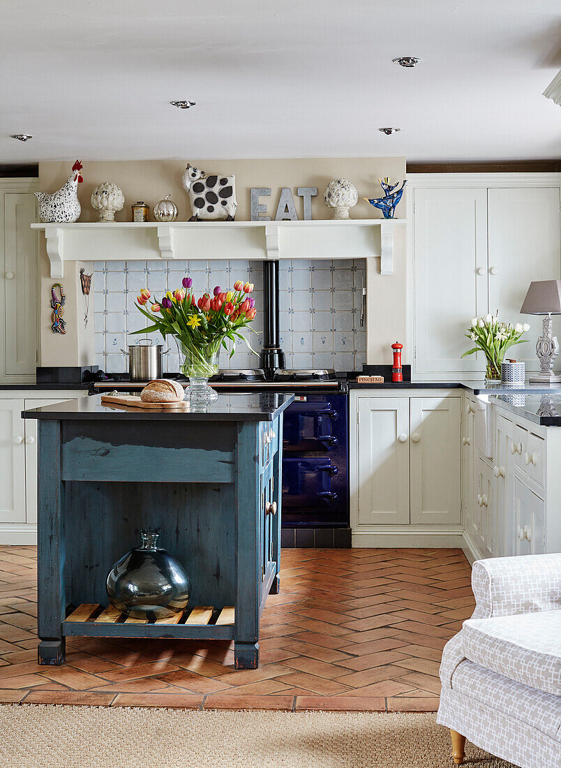 Teal island unit and brick floor in Devon kitchen, UK