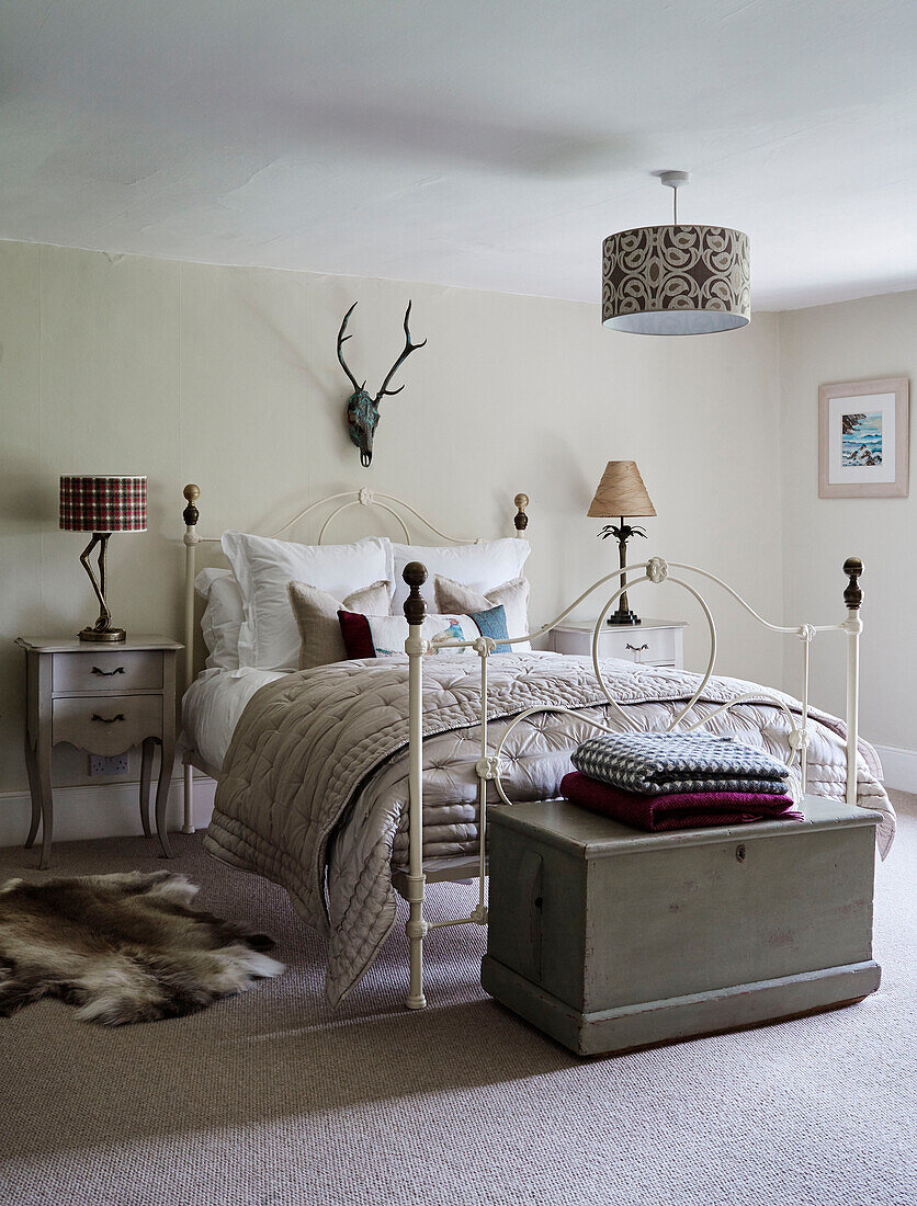 Folded blankets at foot of metal framed bed in Devon home, UK