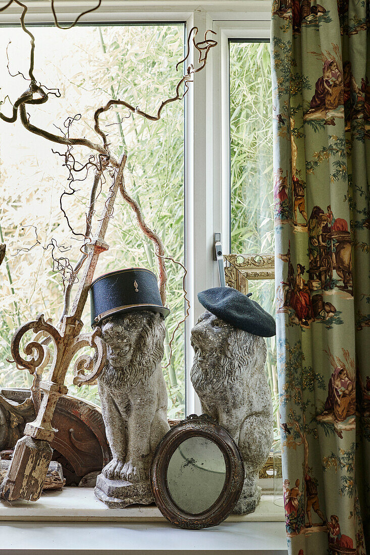 Lion statues wearing hats on Somerset windowsill, UK