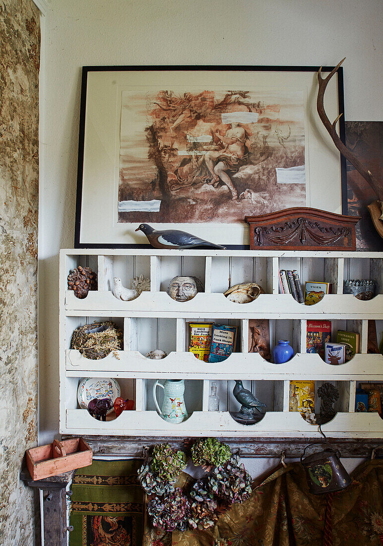 Vintage-Ornamente und Bücher mit gerahmten Drucken in einem Wandregal Somerset, UK