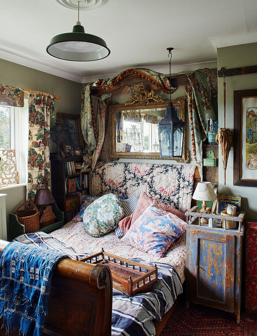 Antique bed with assorted fabrics and mirror in Somerset home, UK
