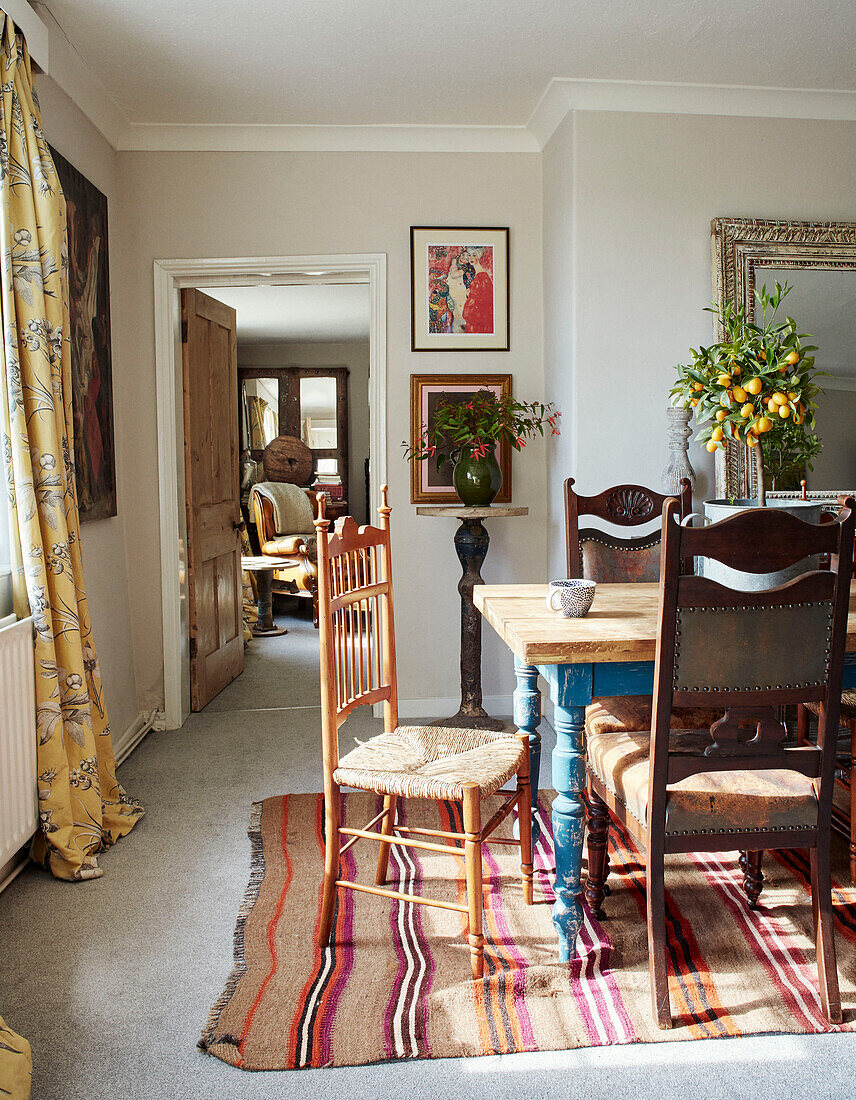 Dining chairs at table on striped rug in North Yorkshire farmhouse, UK