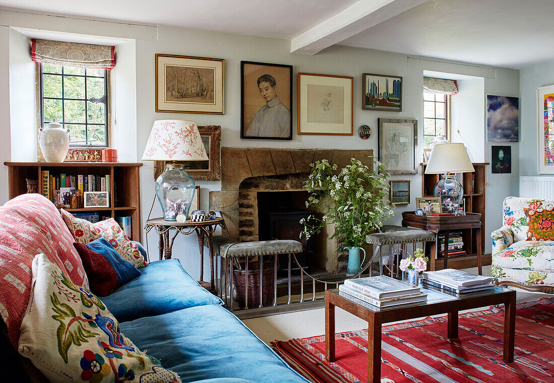 Blue sofa and leaded glass windows with stone fireplace in Oxfordshire farmhouse, UK