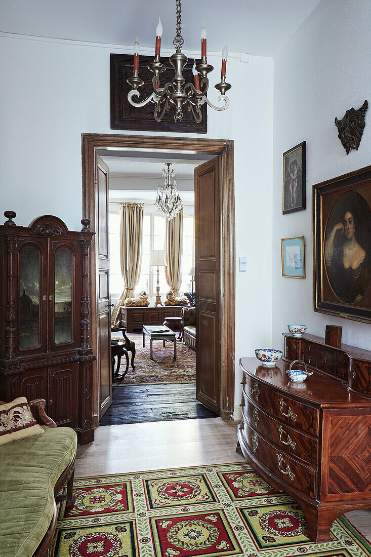 Kronleuchter und antike Möbel mit Blick durch eine Doppeltür in einem Stadthaus in Foix, Ariege, Frankreich