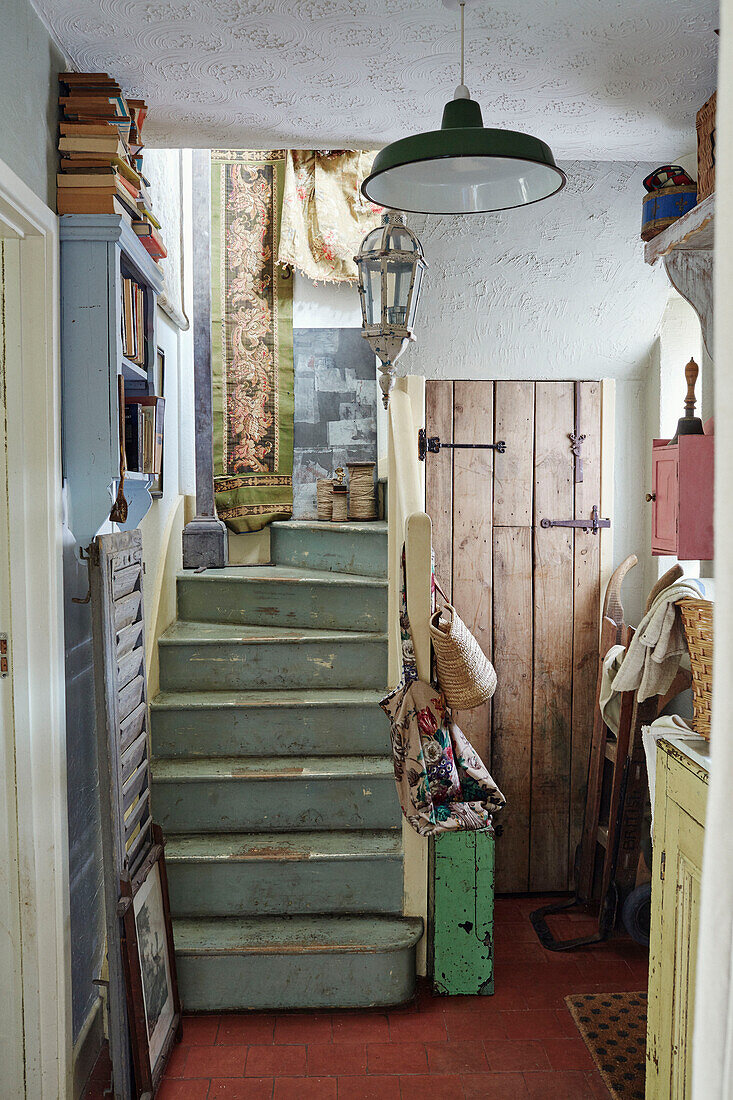 Bücherregal und Schubkarre in einer Eingangshalle in Somerset mit grün gestrichenen Treppen, UK