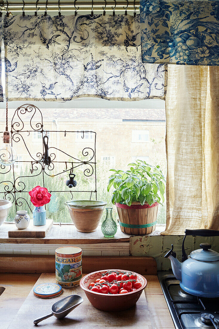 Basilikum und Tomaten mit Stoffen im Fenster der Küche in Somerset, UK
