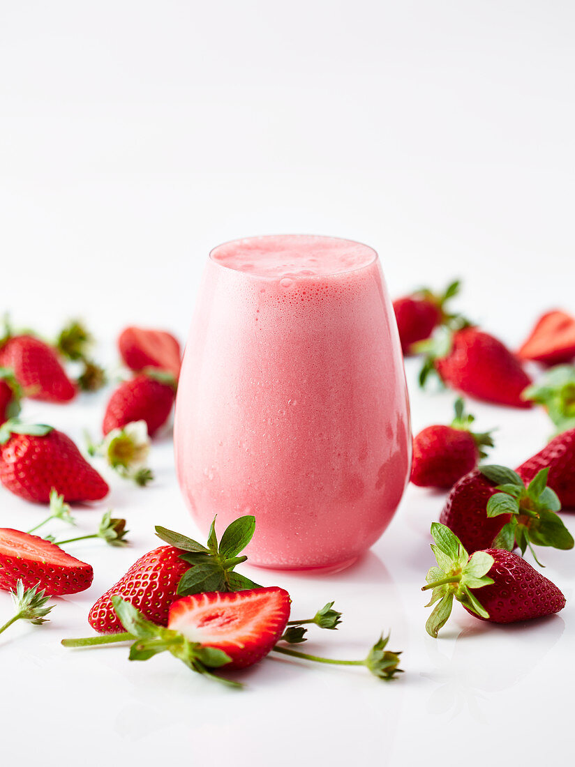 Ein Erdbeersmoothie umgeben von Erdbeeren