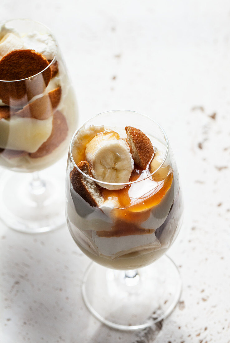 Glasses with banana pudding - sliced bananas, wafer cookies, vanilla pudding, whipped cream and caramel sauce