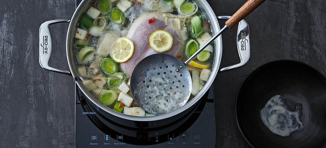 Foam being removed from chicken broth