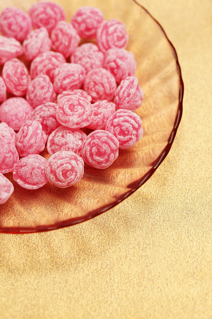 Schälchen mit rosafarbenen Bonbons in Rosenblütenform