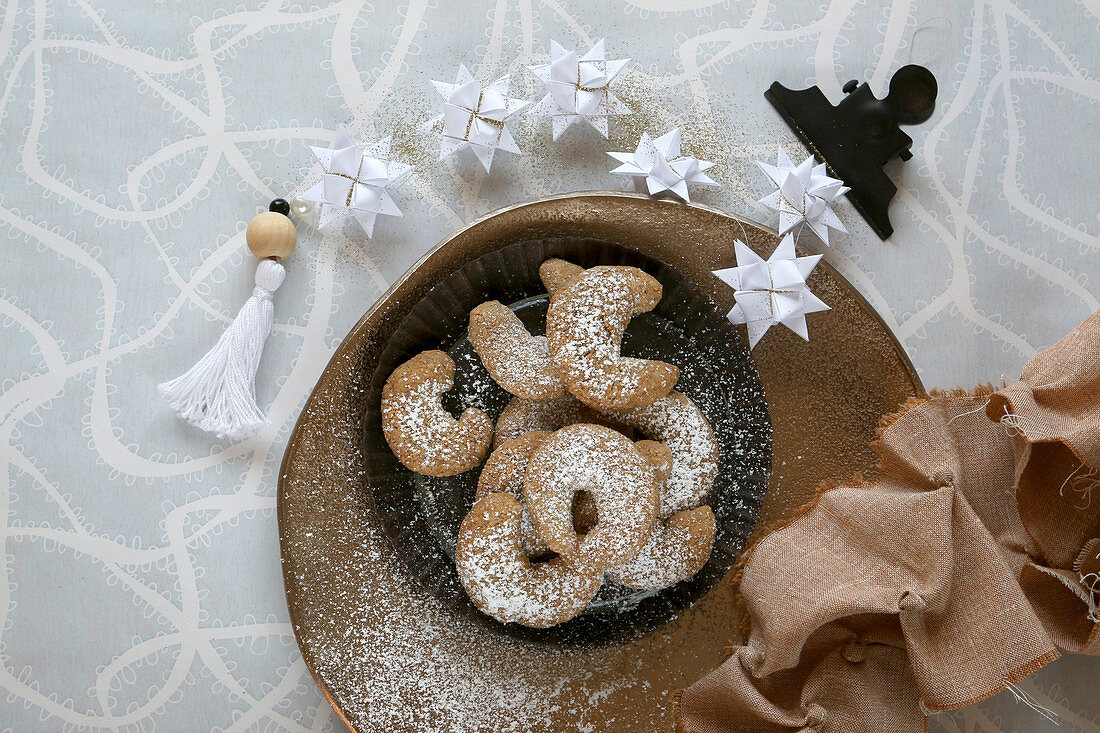 Selbstgebackene glutenfreie Vanillehörnchen mit Puderzucker und Weihnachtsschmuck aus Fröbelsternen