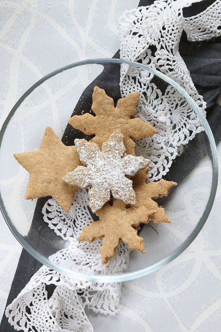 Homemade, gluten-free almond biscuits on a glass plate with a lace doily for Christmas