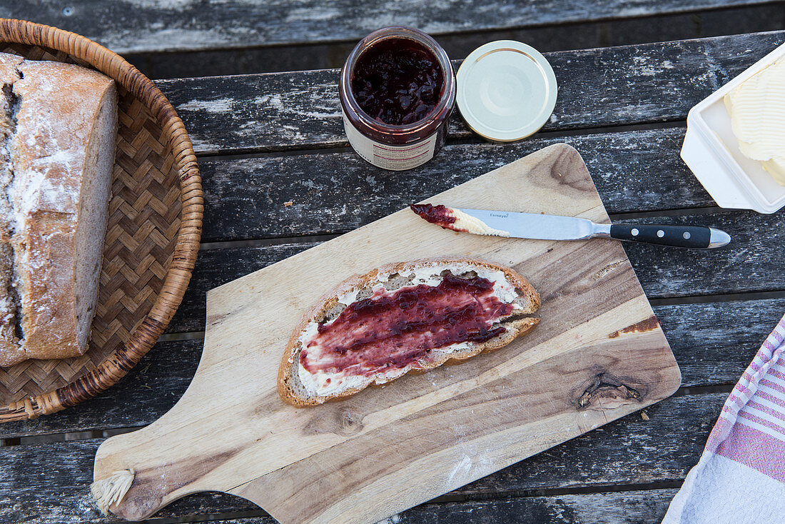 Eine Scheibe Sauerteigbrot mit Butter und Marmelade auf Tisch im Freien