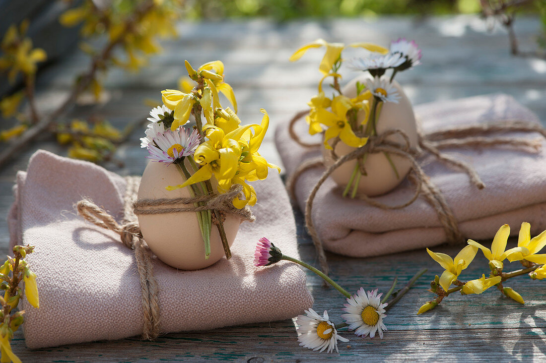 Geschenke zu Ostern : Decken zusammengebunden mit Schnur, Ostereier mit Gänseblümchen und Goldglöckchen als Dekoration