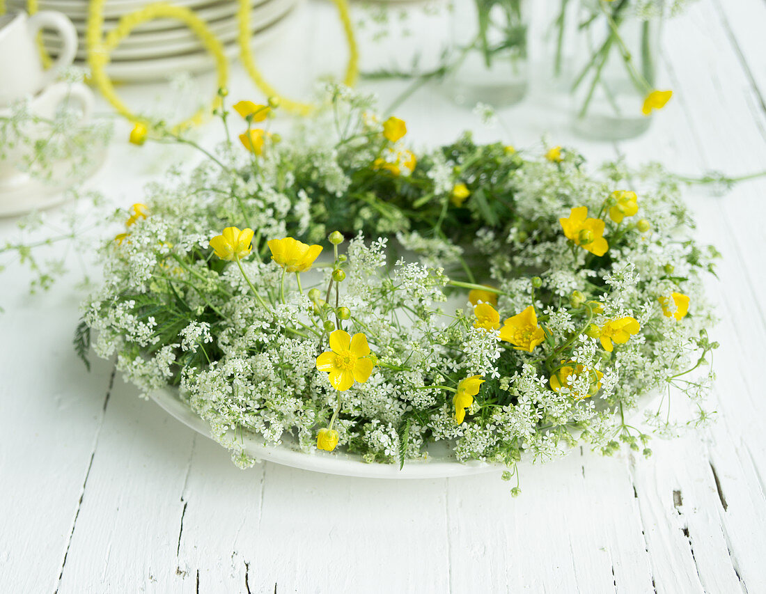 Wreath of cow parsley and buttercups on plate as table decoration for 60th birthday