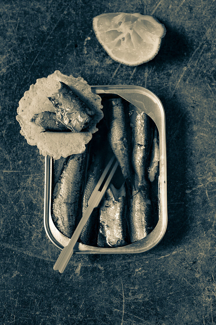 Sardines in a tin with a wooden fork and lime