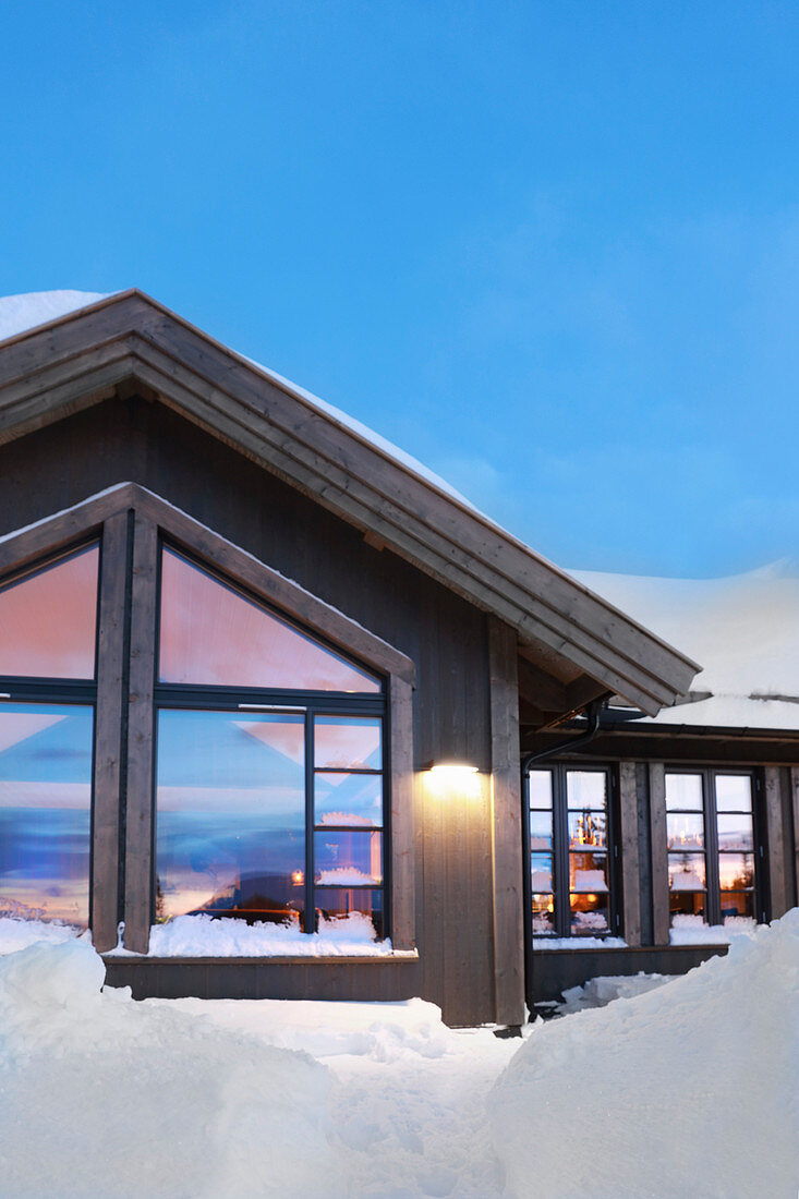 Modern wooden house in snow against blue sky