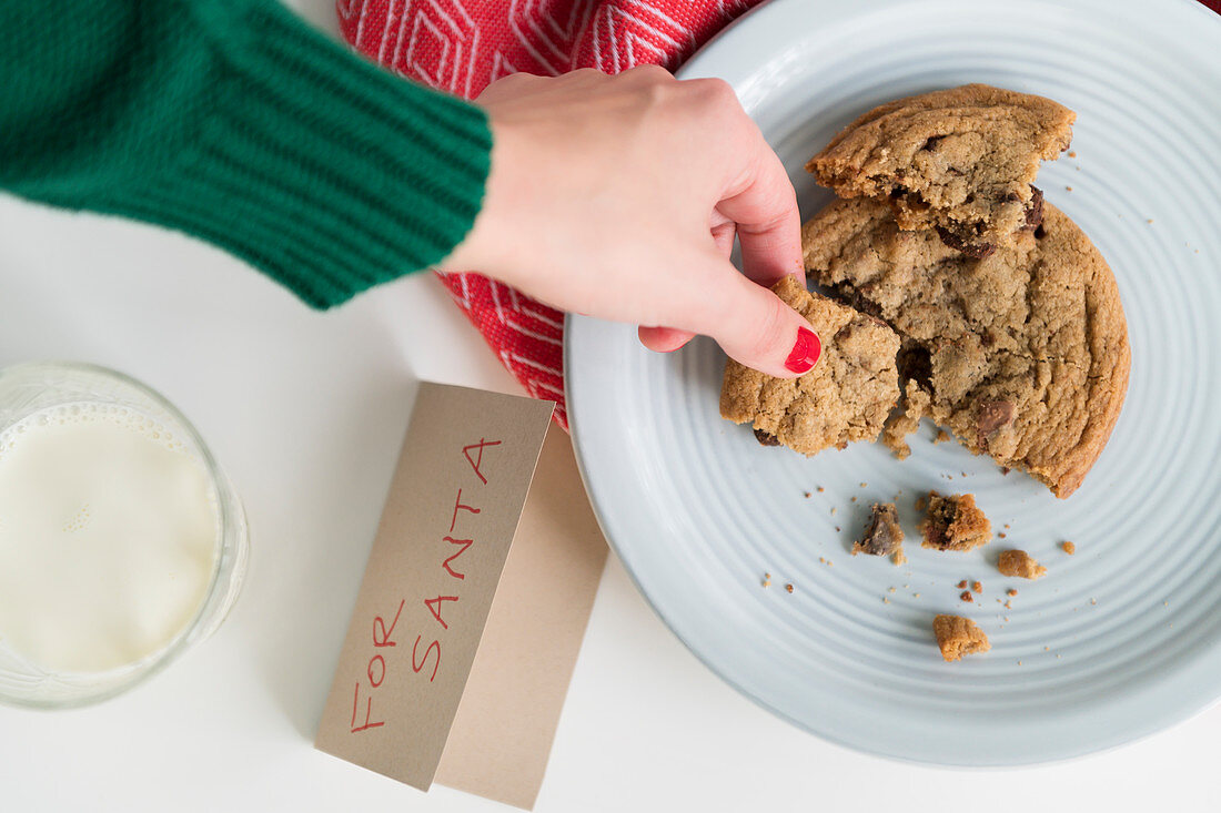 Woman picking up cookie by card for Santa