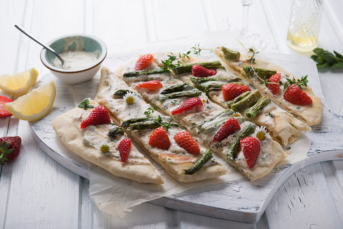 Vegan tarte flambé with cashew nut cream, green asparagus, strawberries and daisies