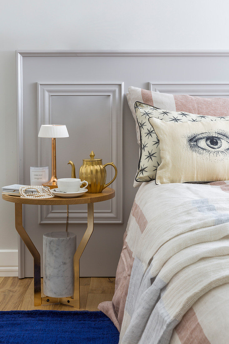 Double bed and round bedside table against panelled headboard