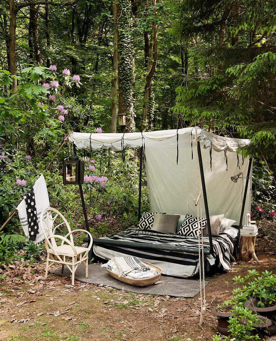 Himmelbett mit schwarz-weißen Accessoires auf einer Waldlichtung