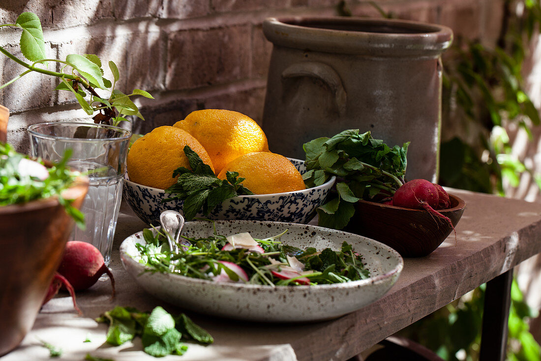 Arugula salad with radishes, shaved asparagus, cheese, mint and lemon dressing on an outdoor stone table